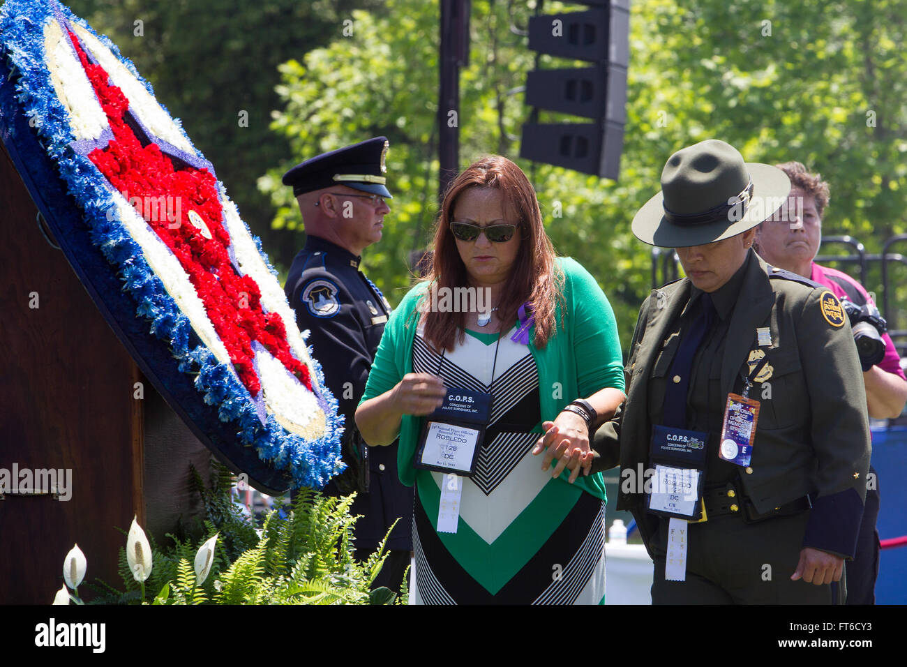 051515: Washington, DC - During Police Week the National Peace Officer's Memorial Service was held at the Capitol in honor of fallen agents and officers across the nation.  The mother of fallen agent Tyler Robledo is escorted by a Border Patrol agent after pinning a memorial flower to the wreath during the Roll Call of Heroes of 2014. Photographer: Donna Burton Stock Photo