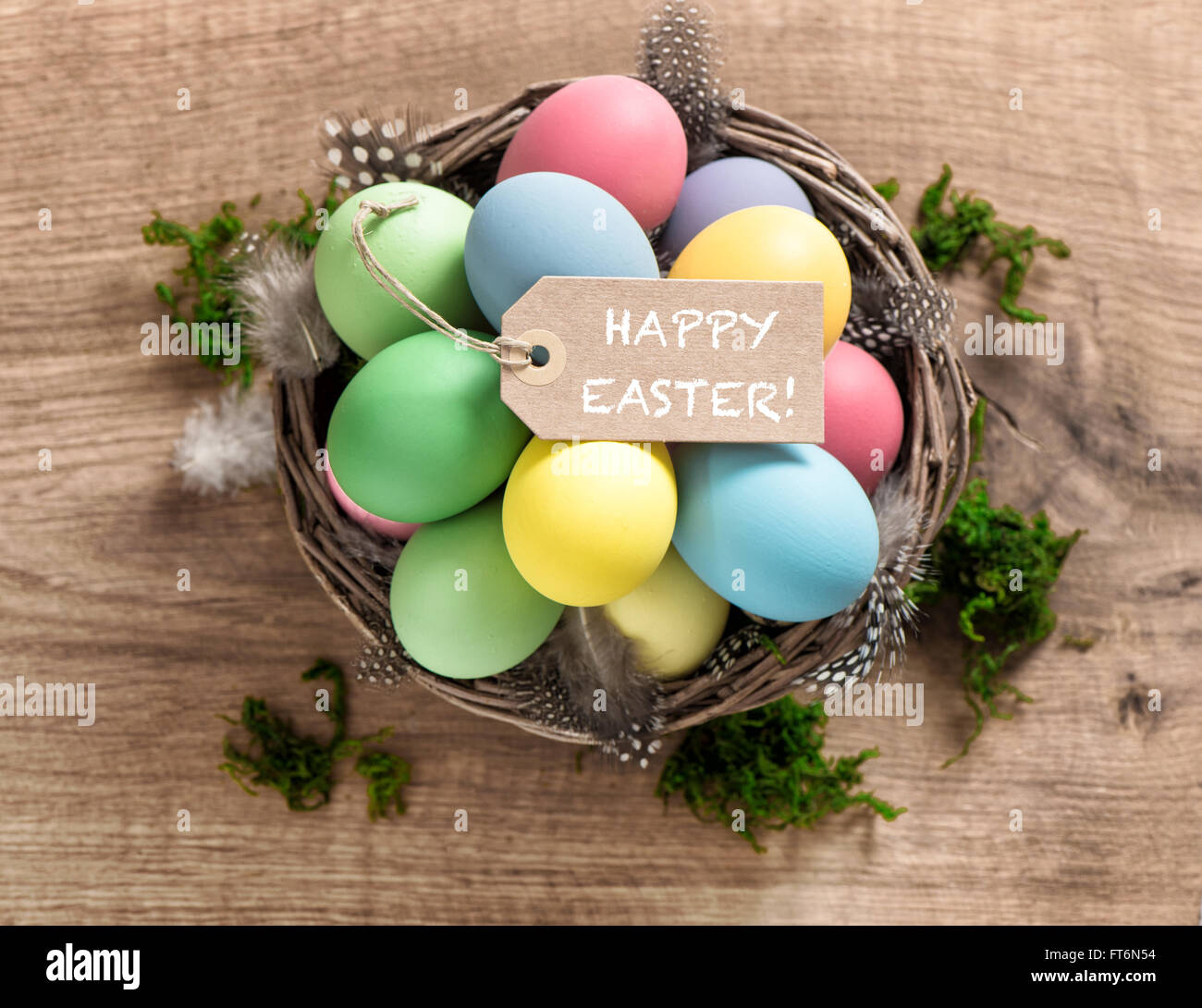 Easter eggs with feather decoration and tag on wooden background Stock Photo