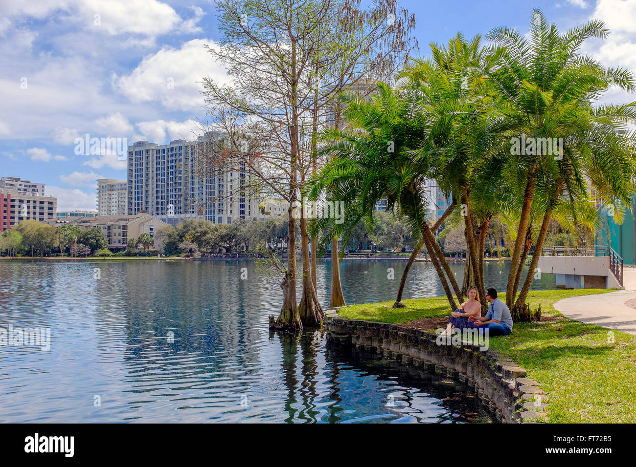 Man and woman sitting at the water's edge of Lake Eola, Downtown Orlando, Florida, America. Stock Photo
