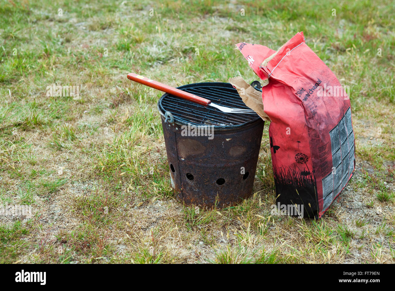 Travel bar B Q or barbecue bucket and coals waiting for its owner in a field. Stock Photo