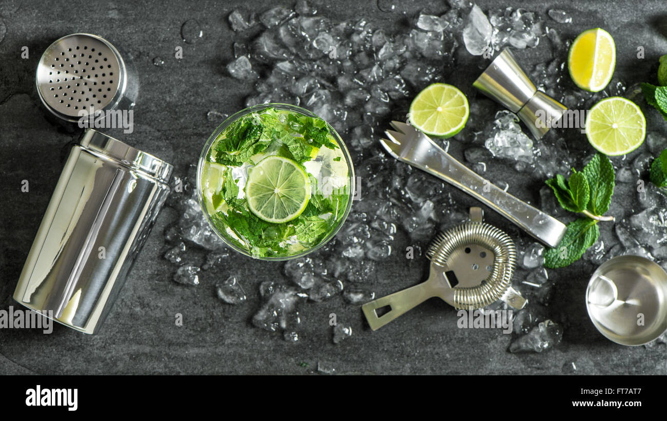 Glass of cocktail with lime, mint, ice. Drink making bar tools, shaker