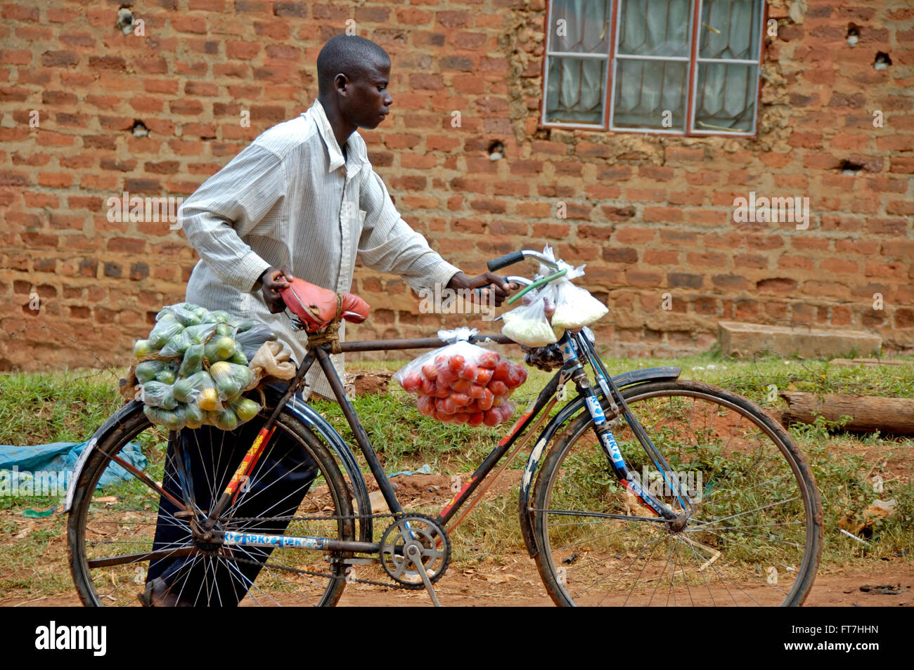 Kampala, Uganda-10 April 2007: Man with bike. He is carrying fruit and vegetables to bring home. Stock Photo