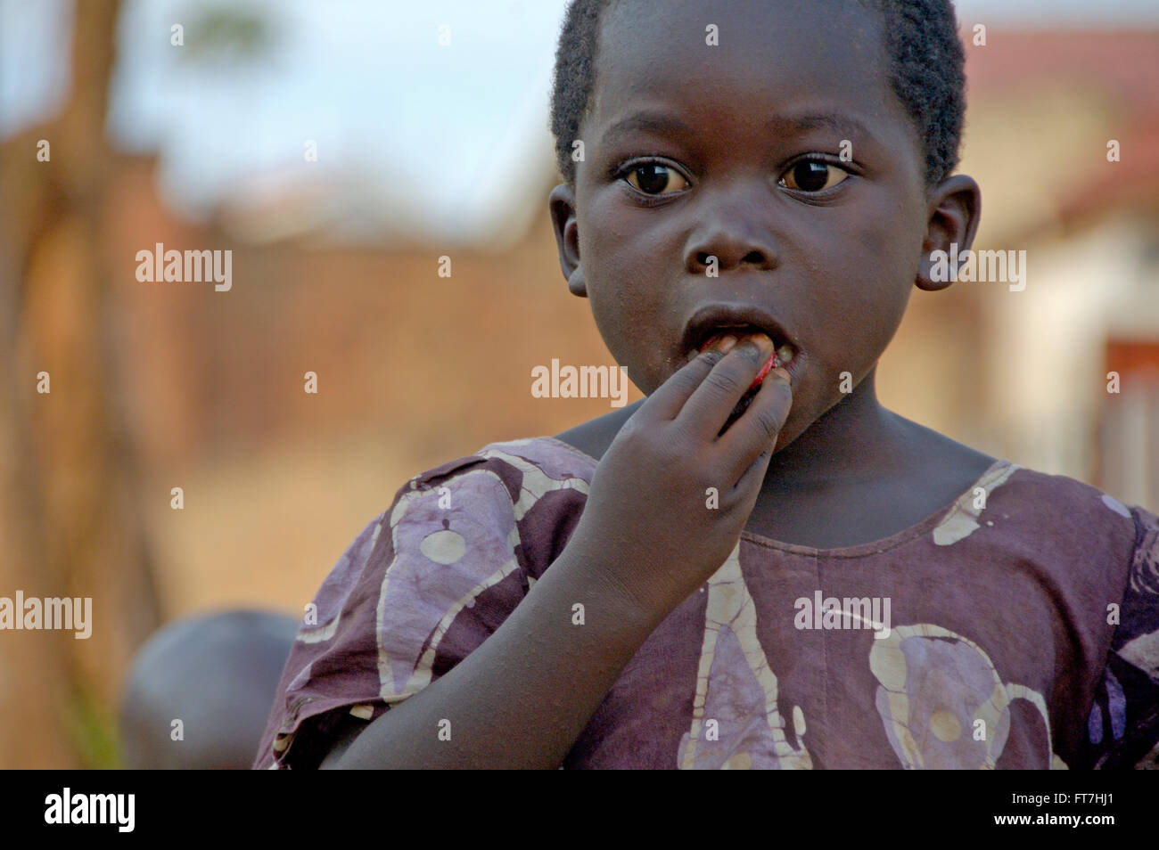 Kampala, Uganda-10 April 2007: Unidentified child is chewing on a top from a coca-cola bottle. The use the top as a candy. Stock Photo