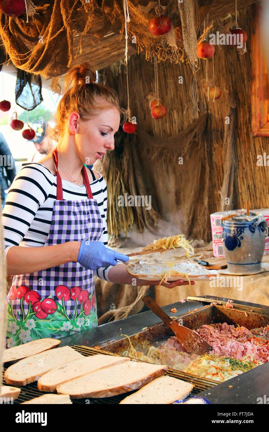 Young woman makes traditional sandwich with lard spread, onions, sausage and cucumbers on the summer fair in downtown Gdansk Stock Photo