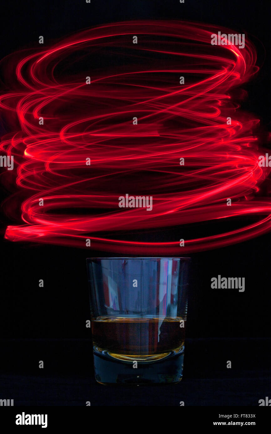 A glass of alcohol possibly whisky surronded by red spinnig light ...