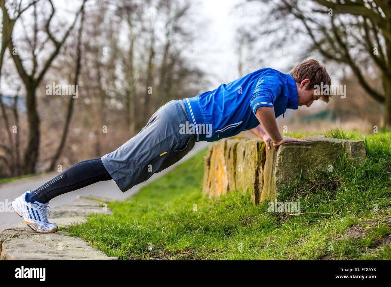 Young man is doing outdoor sports, fitness training, pushups, push ups, Stock Photo