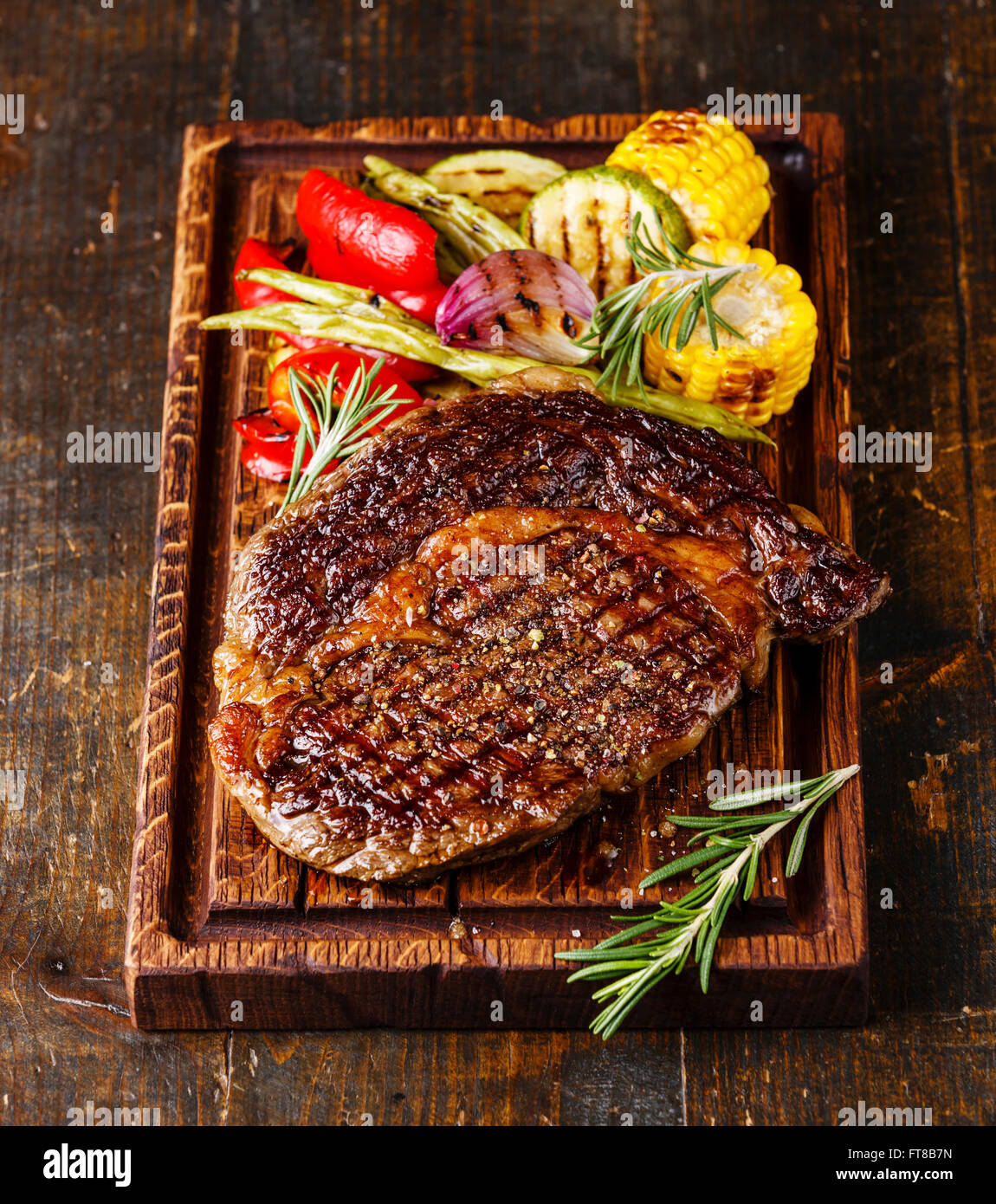 Grilled beef barbecue Ribeye steak and Grilled vegetables on cutting board on dark background Stock Photo