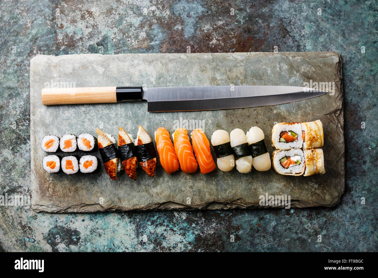 Sushi rolls and nigiri with Japanese knife on stone slate background Stock Photo