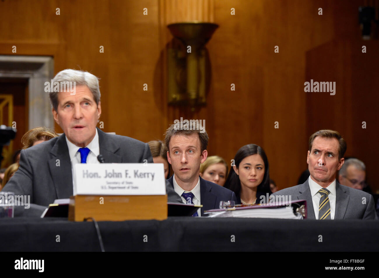 State Department Spokesperson John Kirby (far right) and Deputy Chief of Staff Tom Sullivan listen as U.S. Secretary of State John Kerry delivers his opening statement to the Senate Foreign Relations Committee on February 23, 2016, during an appearance on Capitol Hill in Washington, D.C., to discuss the Obama Administration's 2017 federal budget request. [State Department photo/ Public Domain] Stock Photo