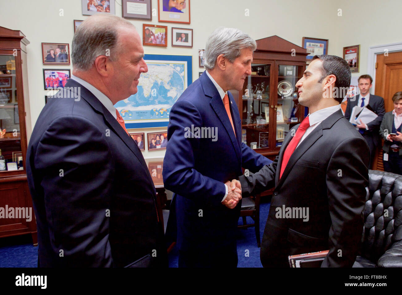 U.S. Secretary of State John Kerry shakes hands with Amir Hekmati, a U.S. citizen who he helped free from unjust detainment in Iran, during a meeting on February 24, 2016, witnessed by U.S. Representative Dan Kildee of Michigan between hearings on Capitol Hill in Washington, D.C. [State Department photo/ Public Domain] Stock Photo