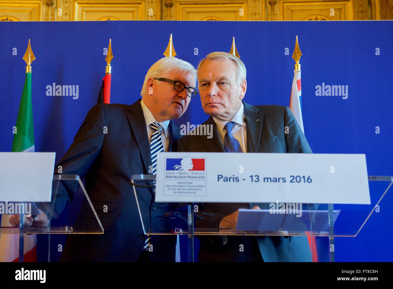 German Foreign Minister Frank-Walter Steinmeier chats with French Foreign Minister Jean-Marc Ayrault on March 13, 2015, at the Quai d'Orsay in Paris, France, as U.S. Secretary of State John Kerry addresses reporters after they held an E4+1 meeting - including representatives of France, Germany, Italy, the United Kingdom, and European Union - focused on Syria, Libya, Yemen, Ukraine, and other foreign policy matters. [State Department Photo/Public Domain] Stock Photo