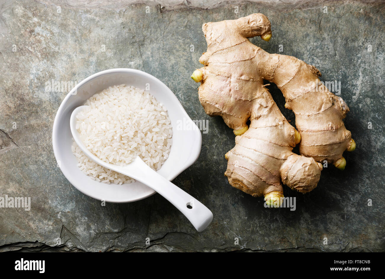 Raw white rice and ginger on gray stone slate background Stock Photo