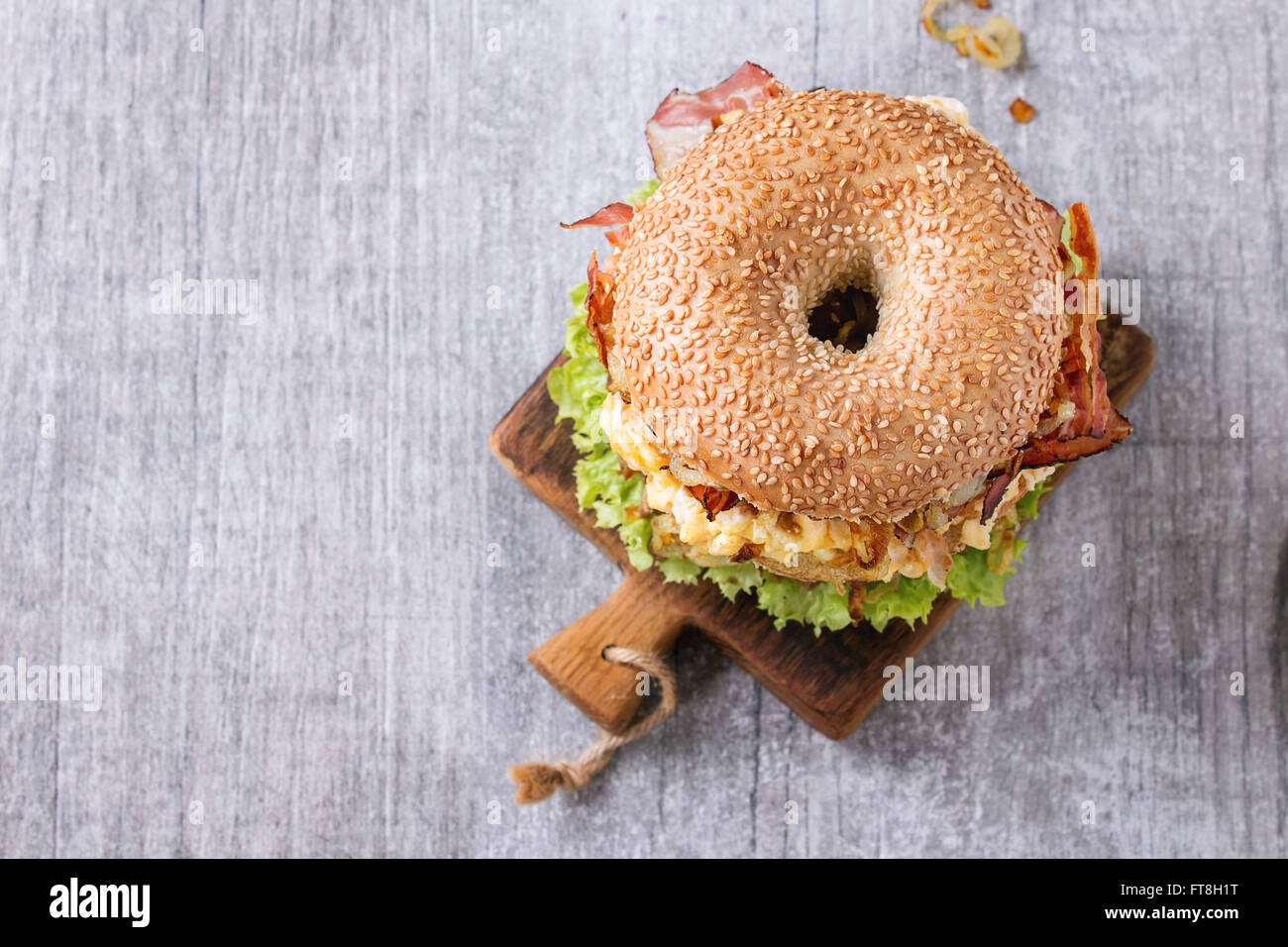 Bagel with stew beef, fresh salad and fried onion on small wooden