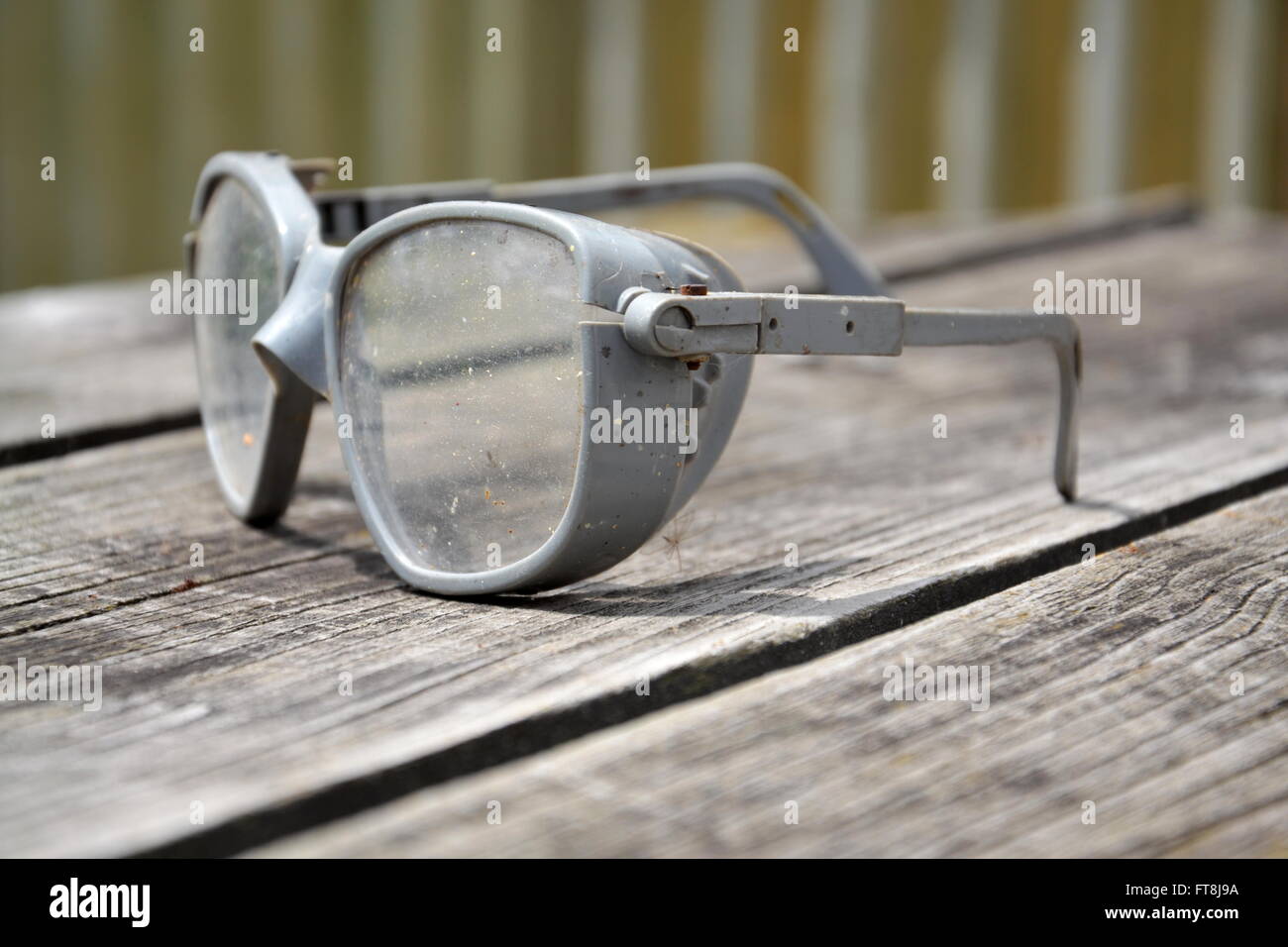 Grey vintage safety glasses on a wooden table Stock Photo