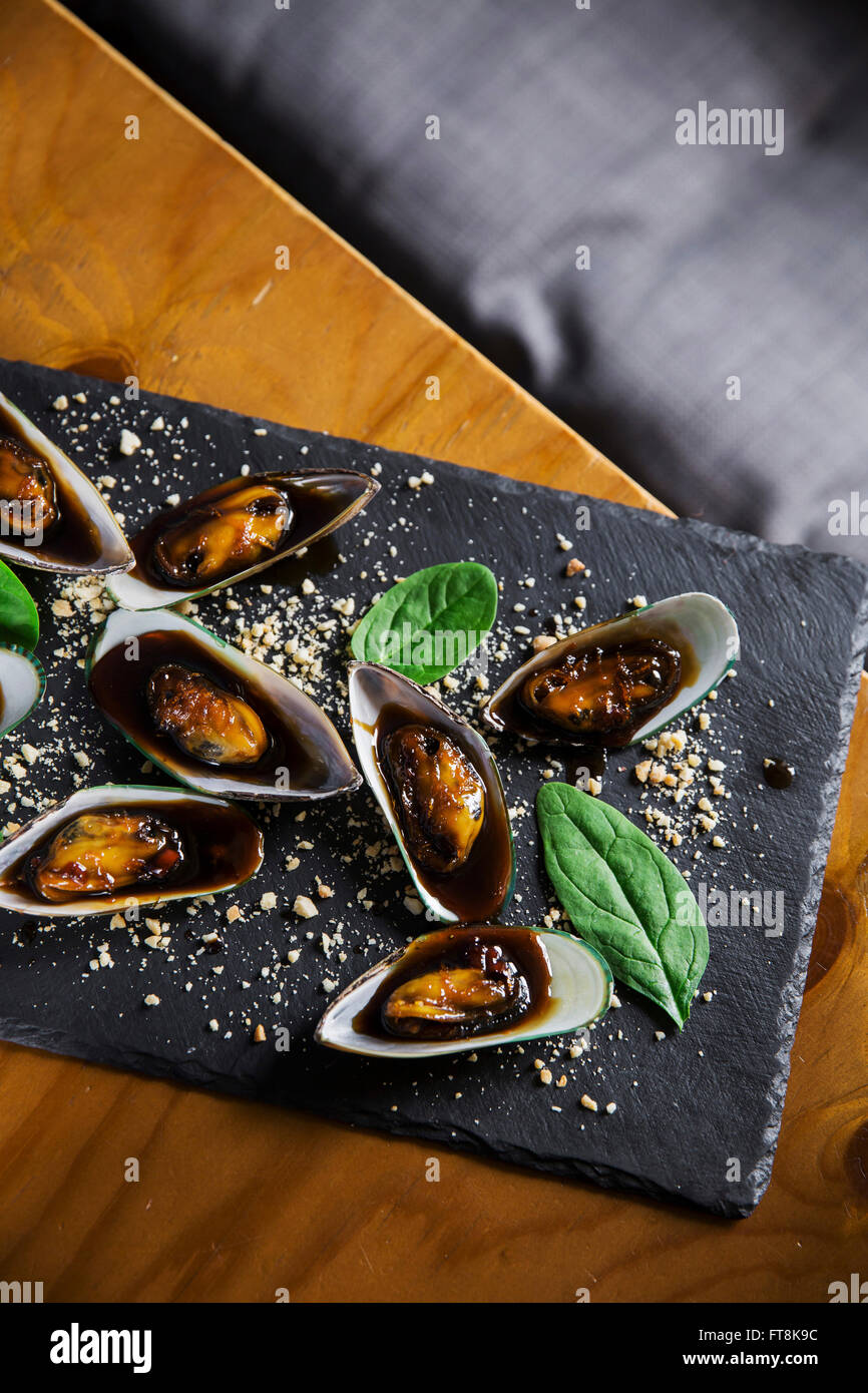 Asian dish - mussels in sticky sweet sauce, with peanuts and spinach Stock Photo