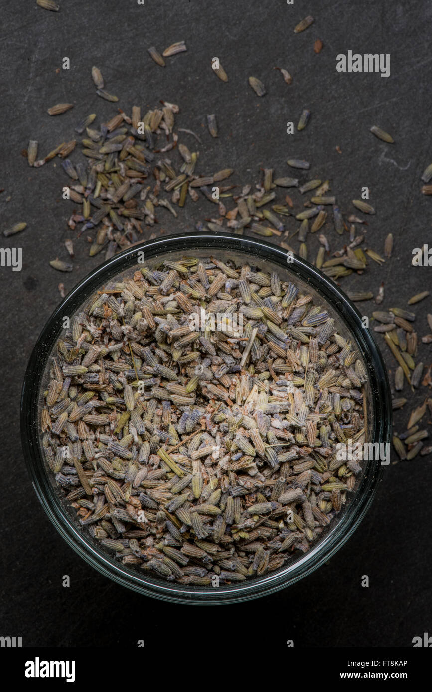 Dried lavender in bowl will spill over onto slate cutting board Stock Photo