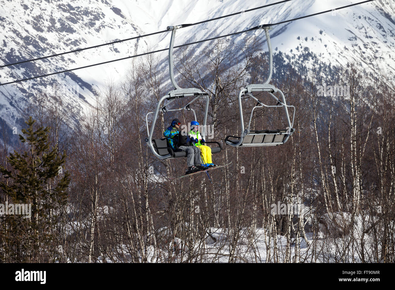 Father and daughter on chairlift at nice sunny day. Caucasus Mountains