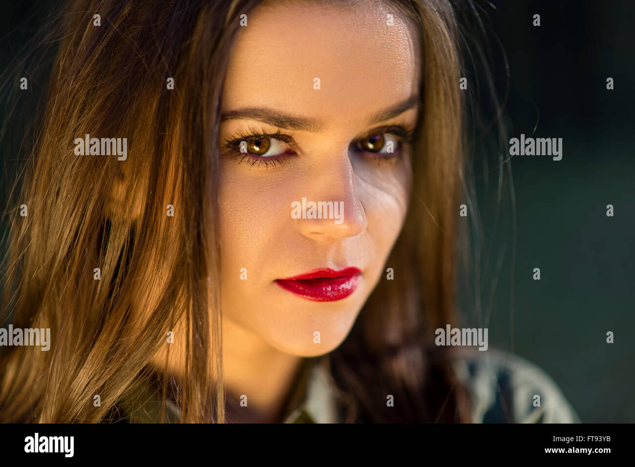 Hint on smile. A close-up portrait of a teenage girl with a cold look and a hint of an smile. Girl has red lips and brown eyes. Stock Photo