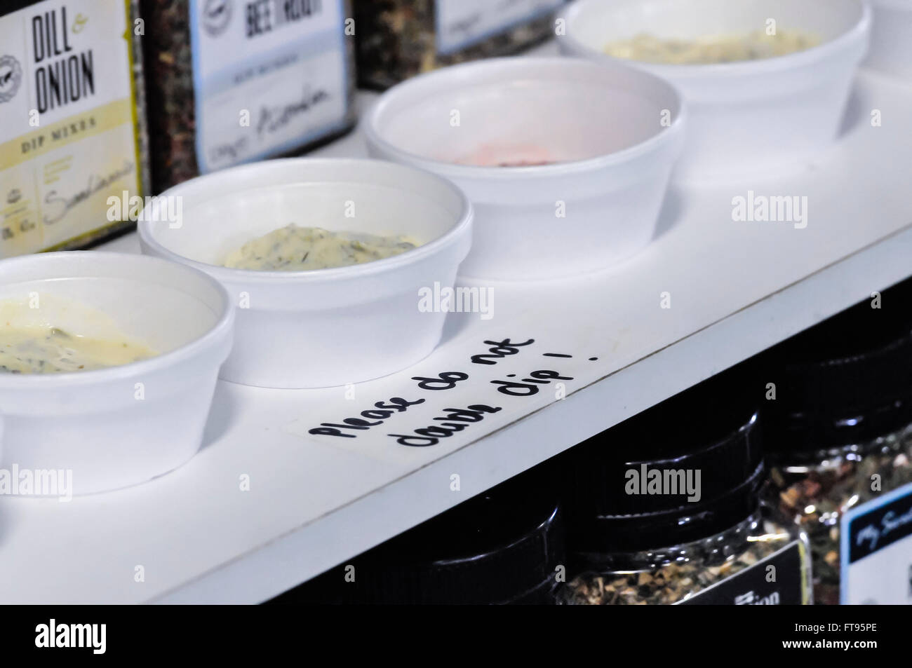 Samples of homemade dips on offer at a market stall with a notice saying 'Please do not double dip!' Stock Photo