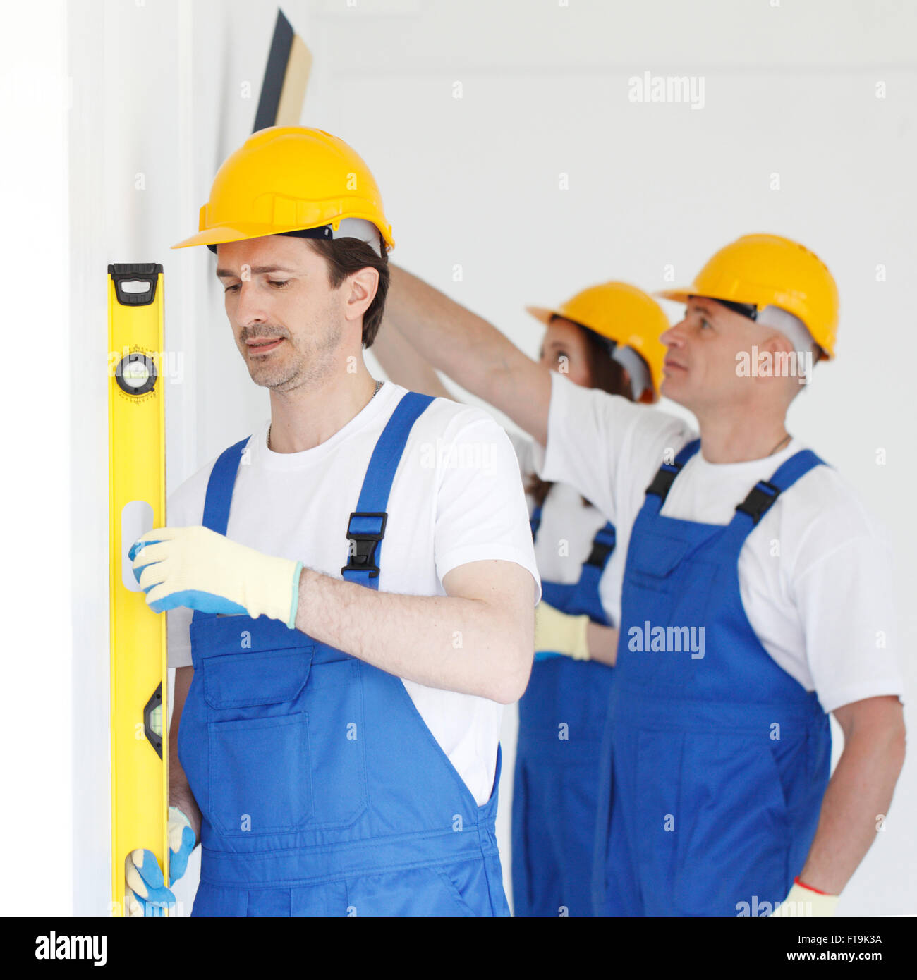 Building teamwork concept - group of smiling builders in hardhats with tools indoors Stock Photo