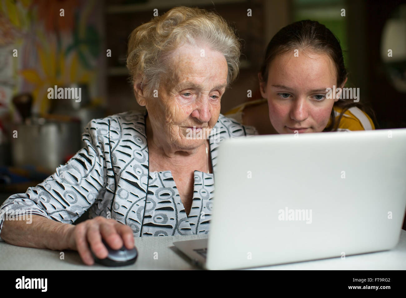 Elderly woman with her granddaughter working on laptop. Stock Photo