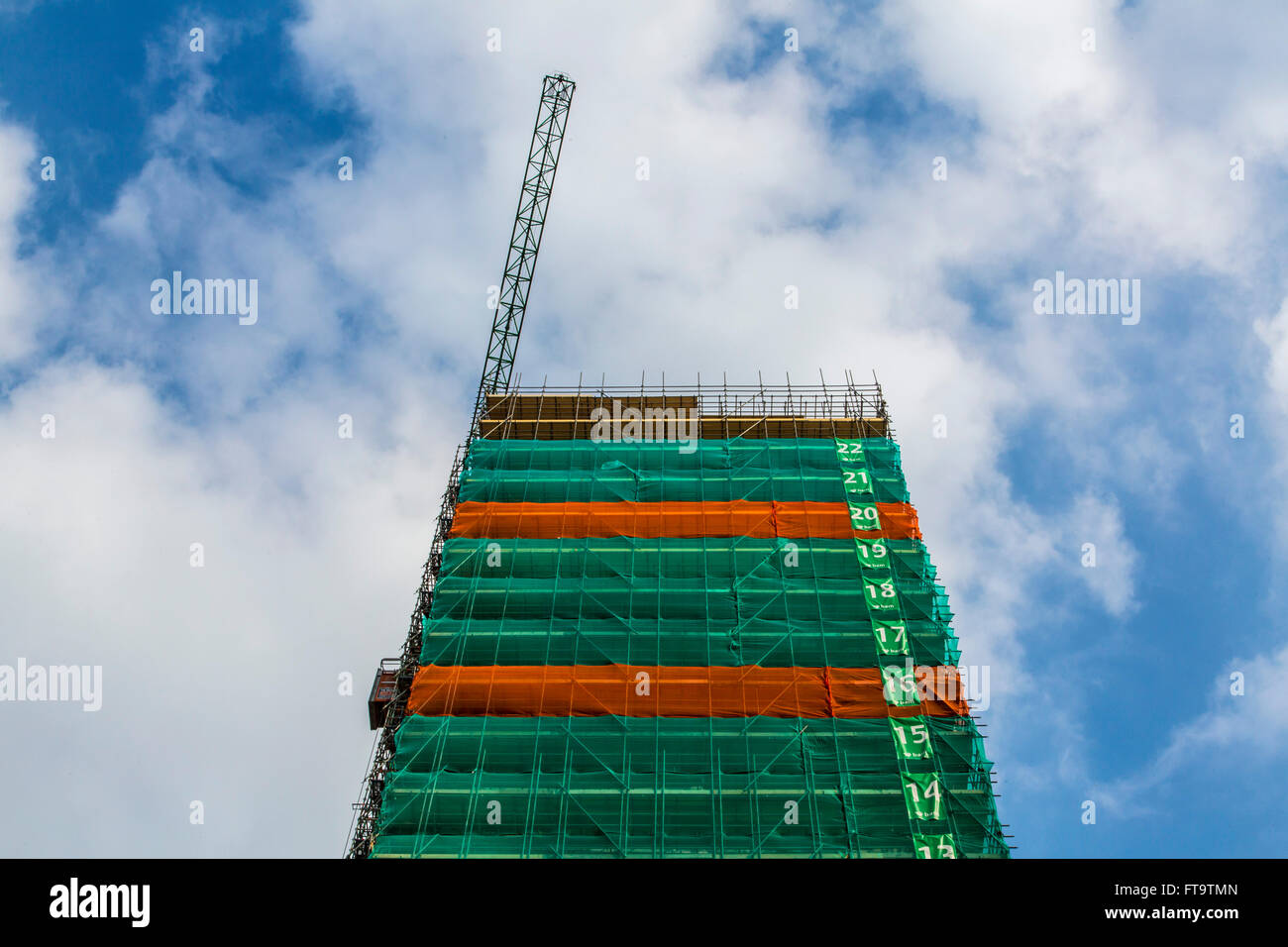 Construction site of a tall building, skyscraper, numbered floors, tarp around the building, Stock Photo