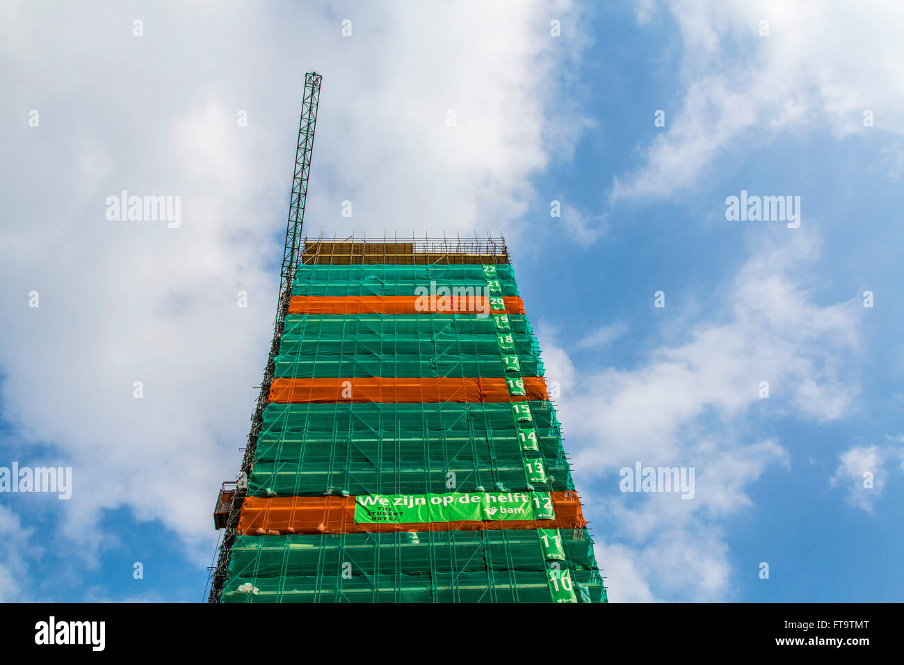 Construction site of a tall building, skyscraper, numbered floors, tarp around the building, Stock Photo