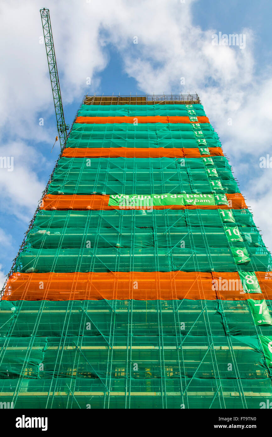 Construction site of a tall building, skyscraper, numbered floors, tarp around the building, Stock Photo