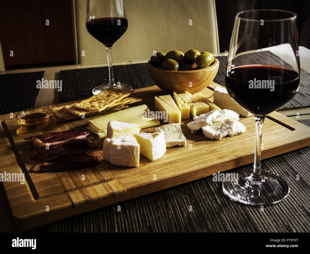 Camembert, Gouda And Brie Cheese Platter With Wine Glasses Stock Photo
