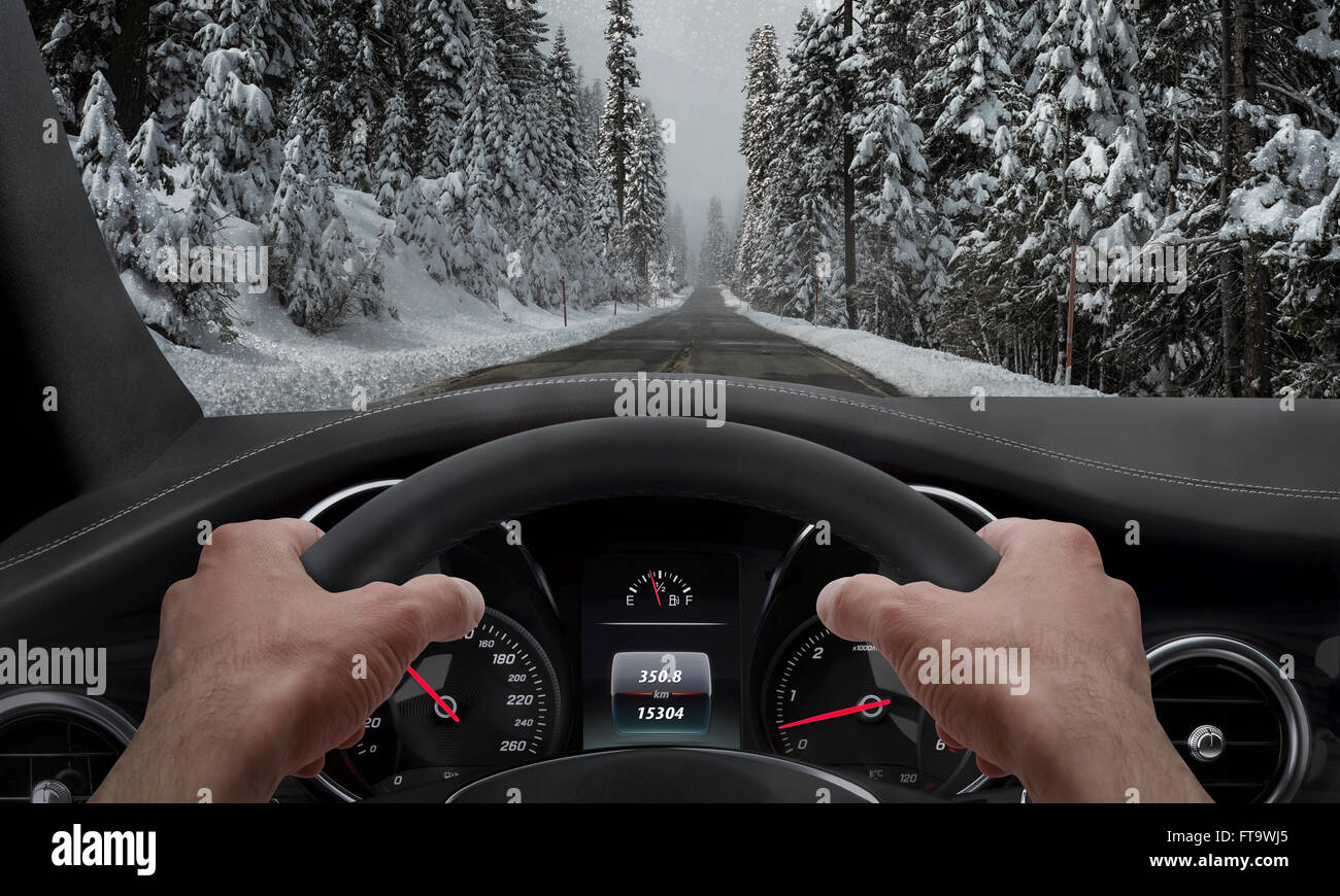 Driving in snowy weather. View from the driver angle while hands on the wheel. Stock Photo