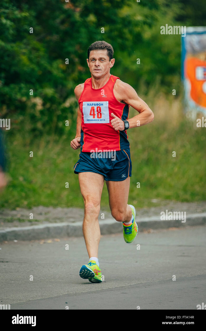 male middle-aged athlete runs through Park during Chelyabinsk marathon Stock Photo