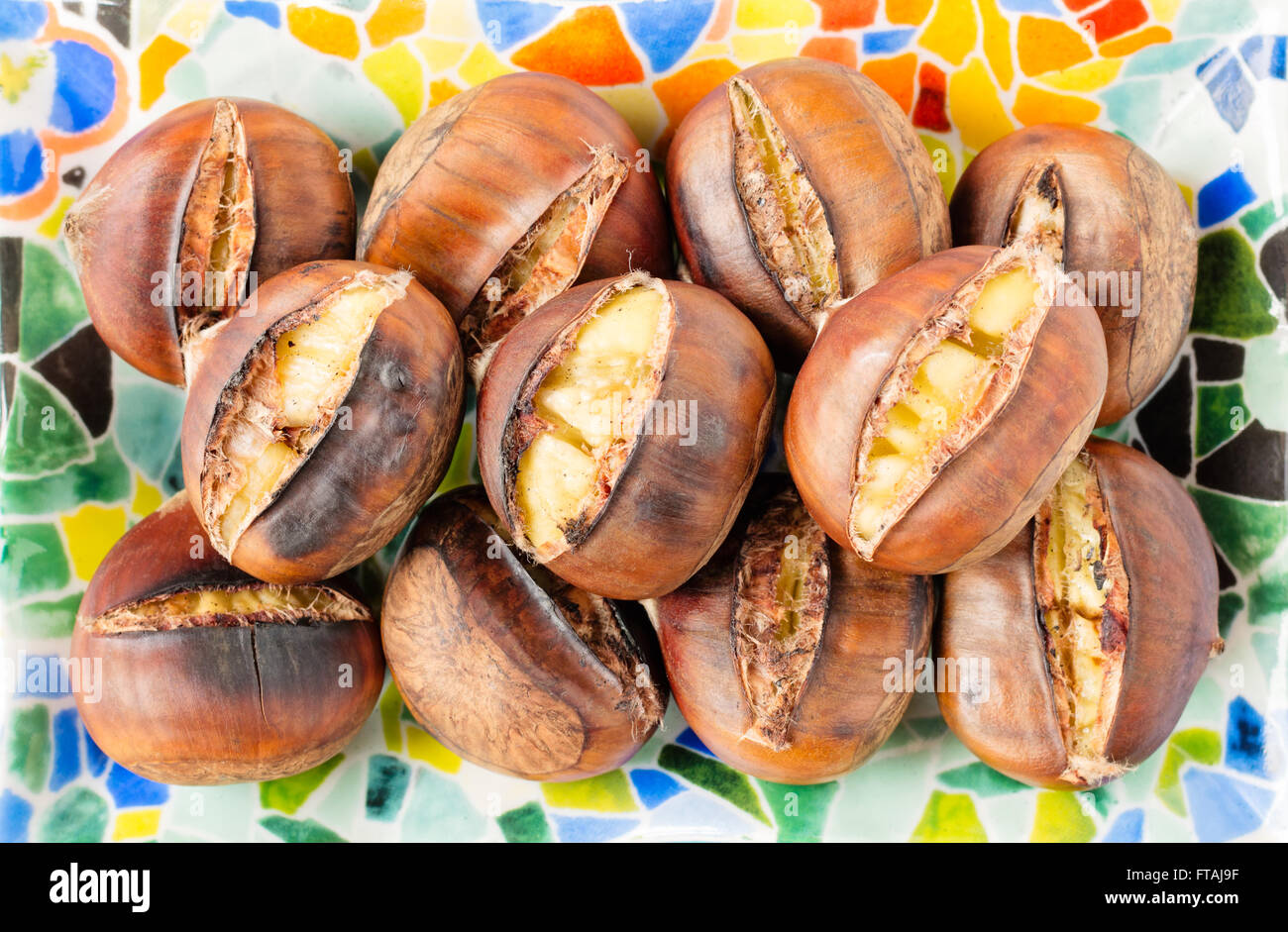 Top view of roasted chestnuts in their shells on a colorful mosaic ...