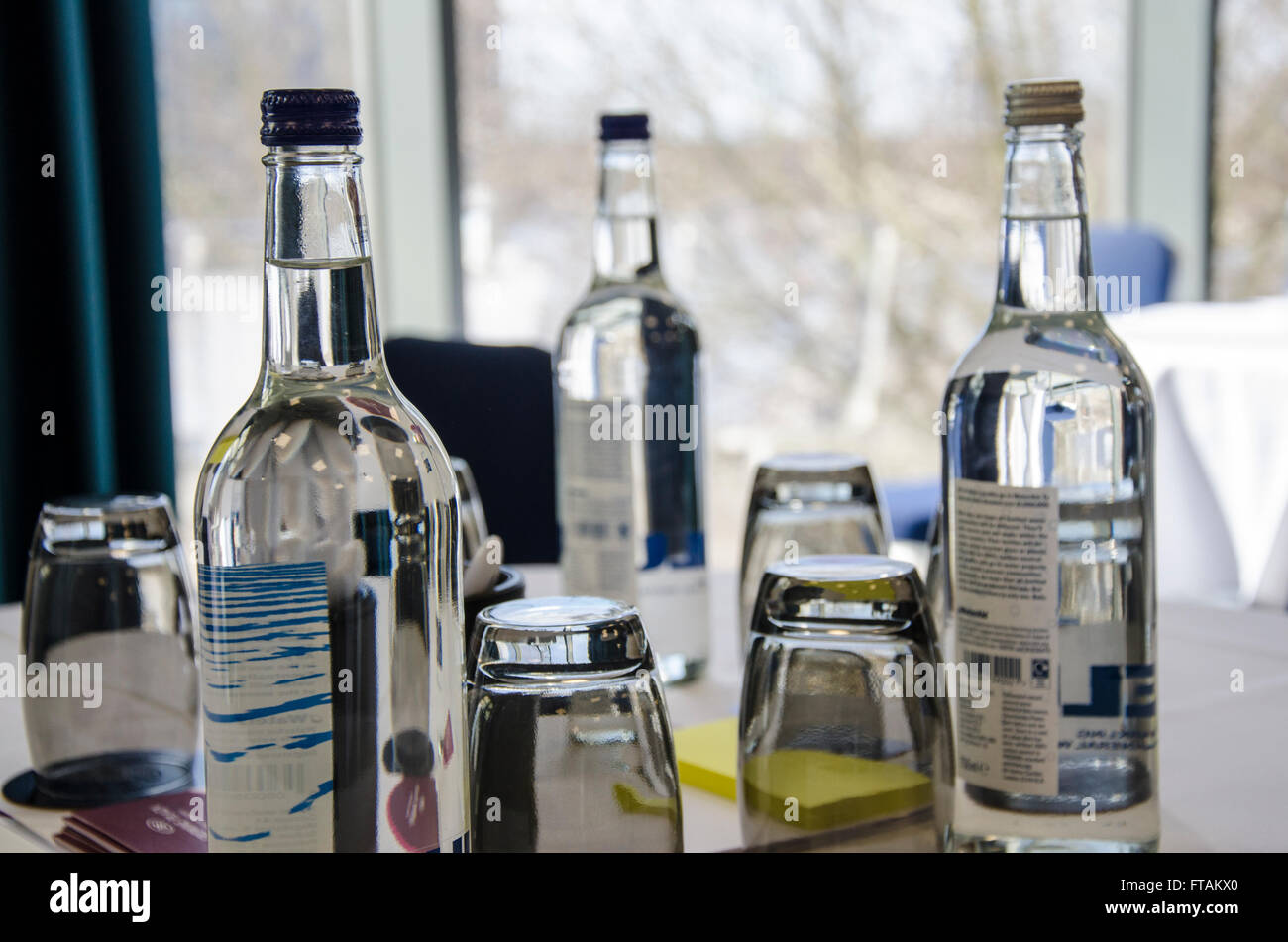 Bottles of mineral water and glasses provided on tables in a conference room. Stock Photo