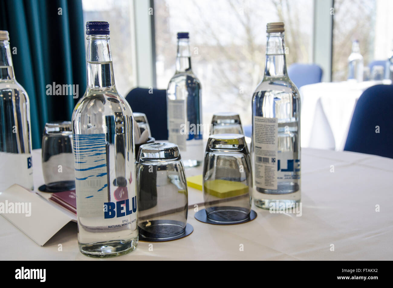 Bottles of mineral water and glasses provided on tables in a conference