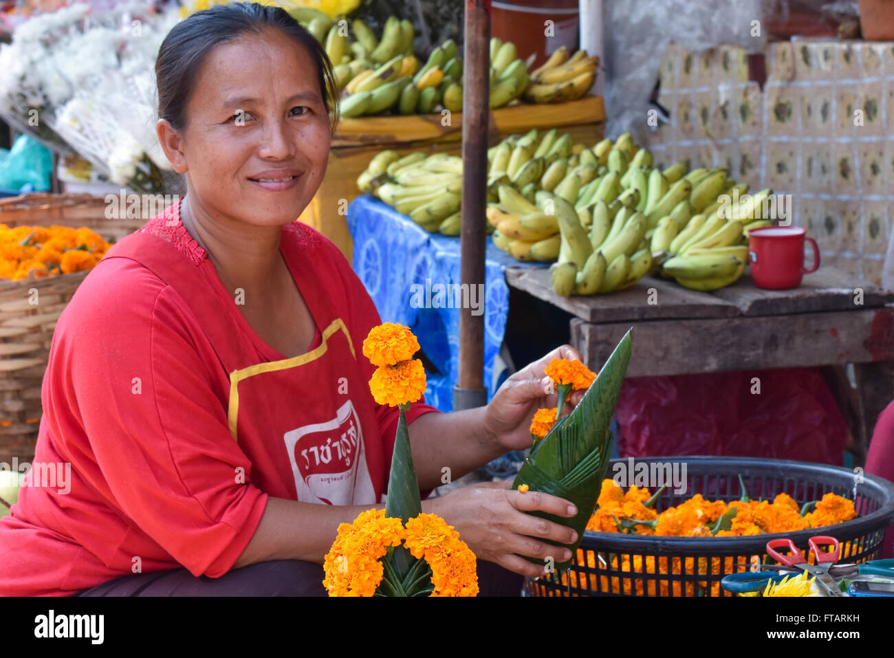 Saleslady Stall selling flowers for Buddhist celebrations downtown Vientiane Laos Stock Photo