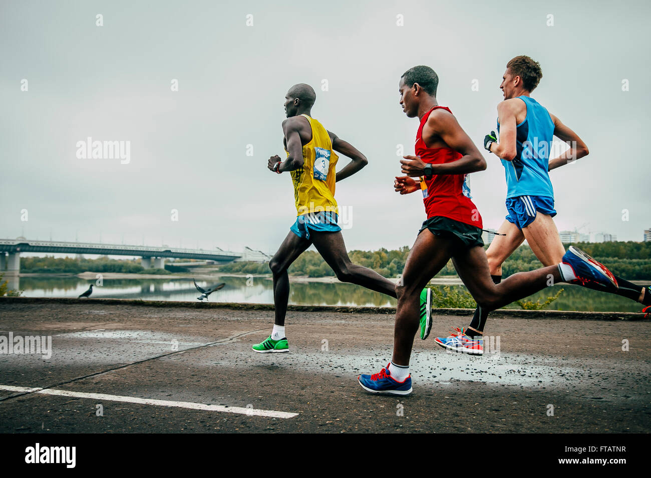 Omsk, Russia -  September 20, 2015: three leaders of race running along embankment river during Siberian marathon Stock Photo