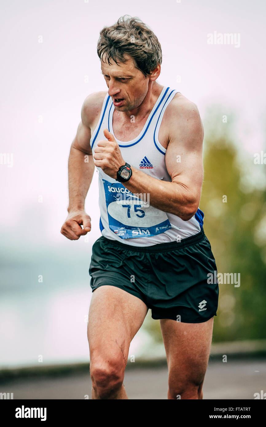 Omsk, Russia -  September 20, 2015: man middle-aged runner runs along rive during Siberian international marathon Stock Photo