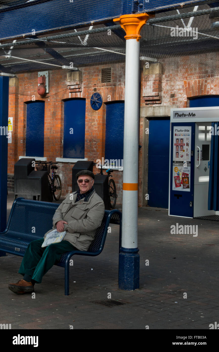 A model released image of an Old Aged Pensioner sitting alone at a railway station in Skegness, Lincolnshire, UK Stock Photo