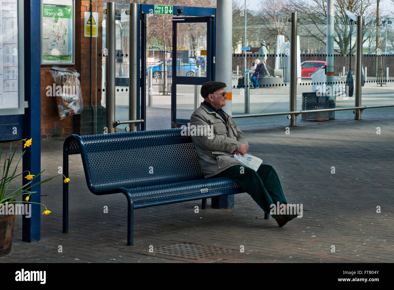 A model released image of an Old Aged Pensioner sitting alone at a railway station in Skegness, Lincolnshire, UK Stock Photo