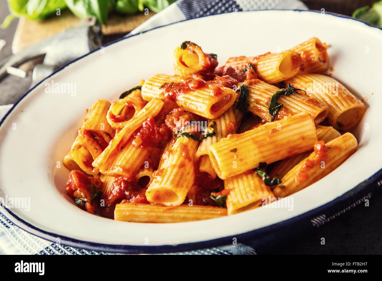 Pasta. Italian and Mediterranean cuisine. Pasta Rigatoni with tomato sauce basil leaves garlic and parmesan cheese. An old home Stock Photo