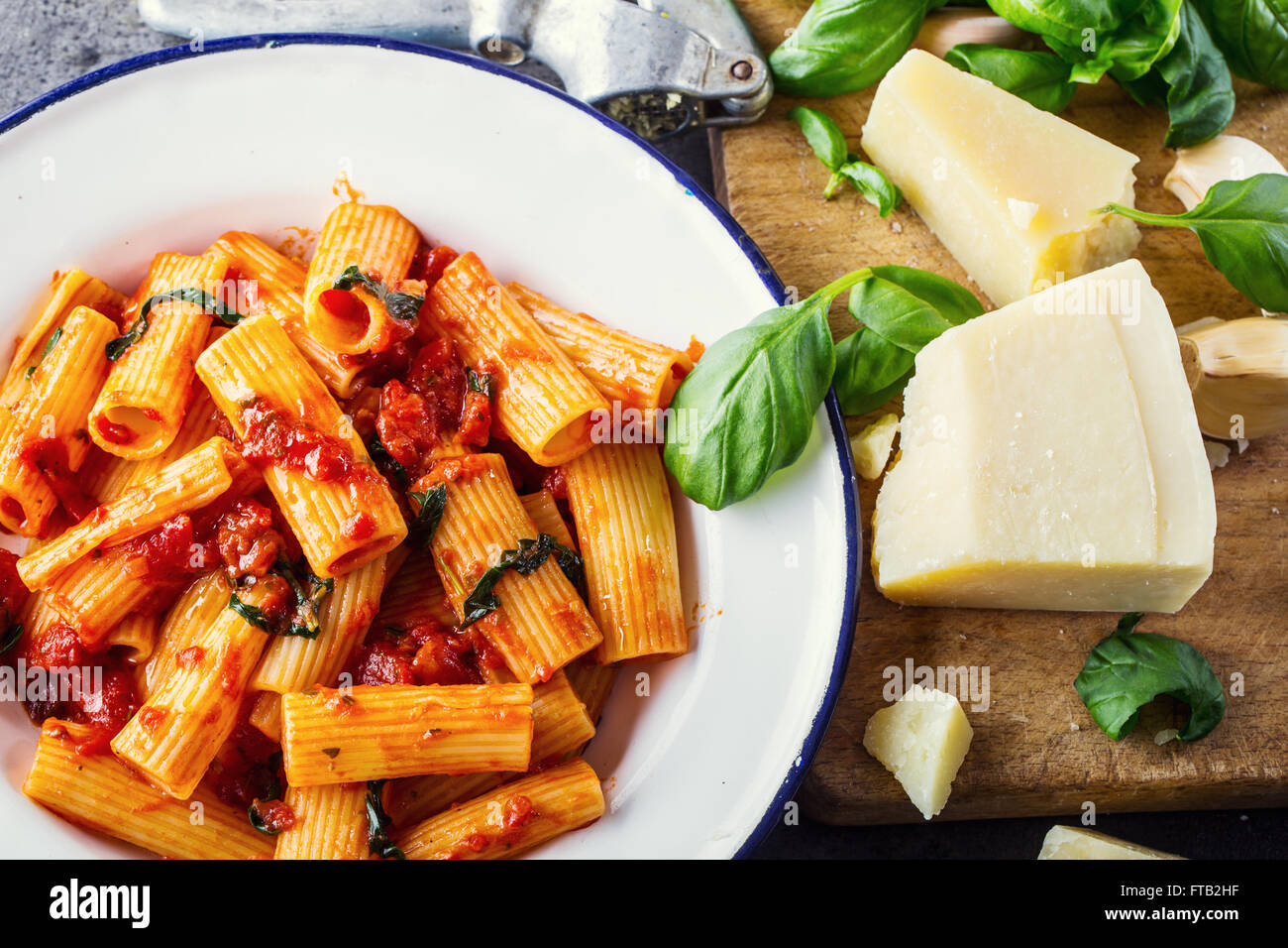 Pasta. Italian and Mediterranean cuisine. Pasta Rigatoni with tomato sauce basil leaves garlic and parmesan cheese. An old home Stock Photo