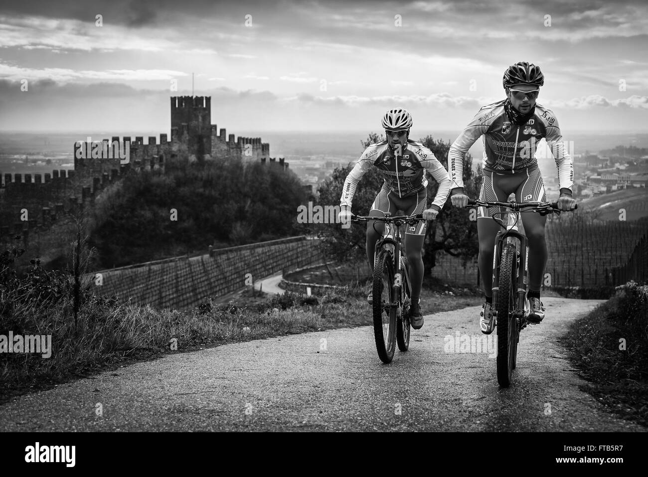 Soave, Italy - March 27, 2016: Cyclists train after a storm on the hills surrounding the castle of Soave. Stock Photo