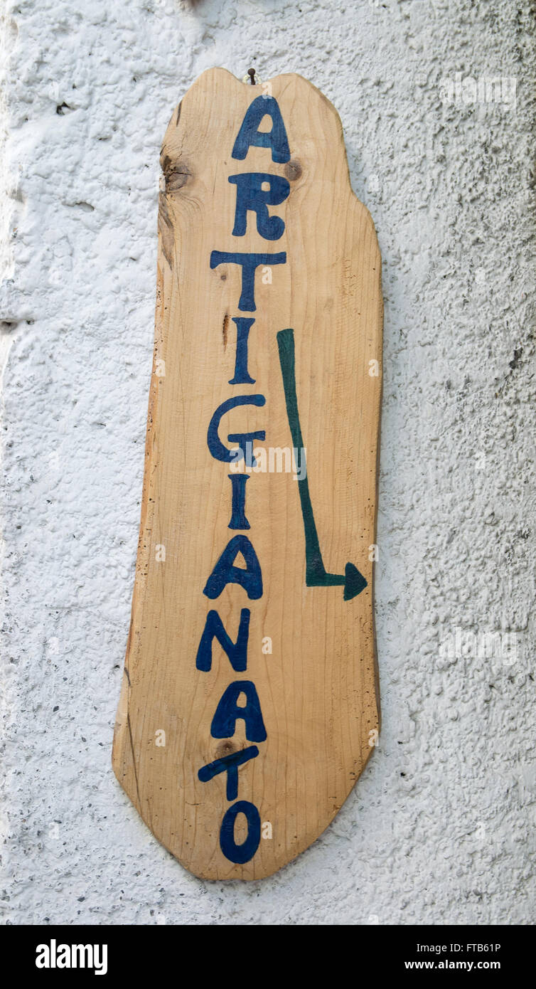 Sign 'Craftsmanship' on wooden board hanging on the wall in Italy. Stock Photo