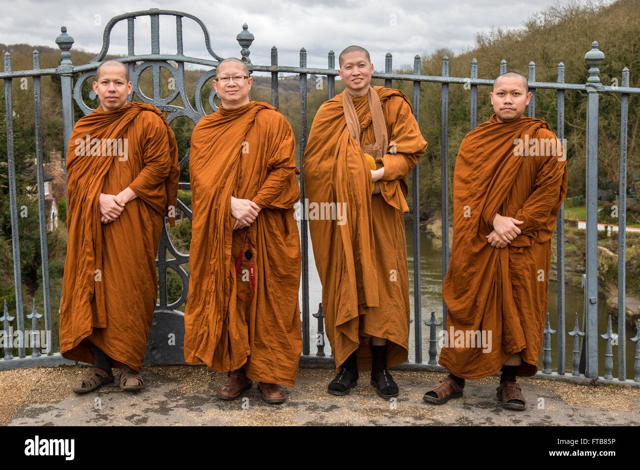 Four monks from Thailand standing on the historic Ironbridge in Shropshire, England. Stock Photo