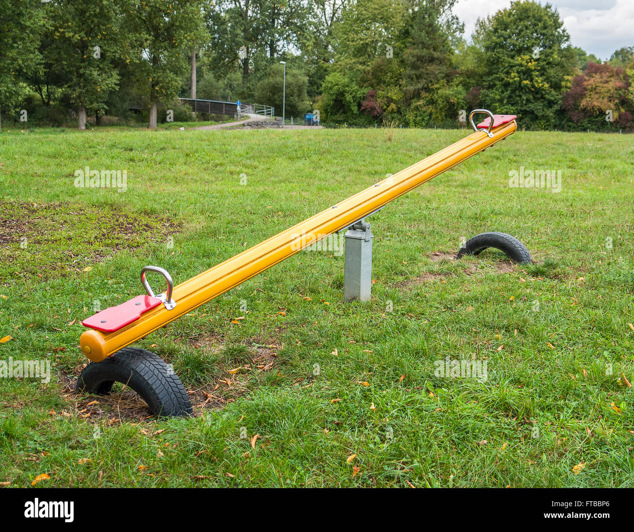 outdoor playground scenery with Seesaw, lawn and trees Stock Photo