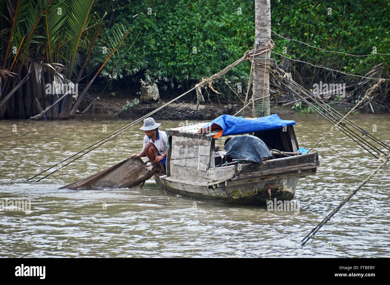 A fisherman pulls in his net in the Mekong Delta near Ben Tre, Vietnam ...