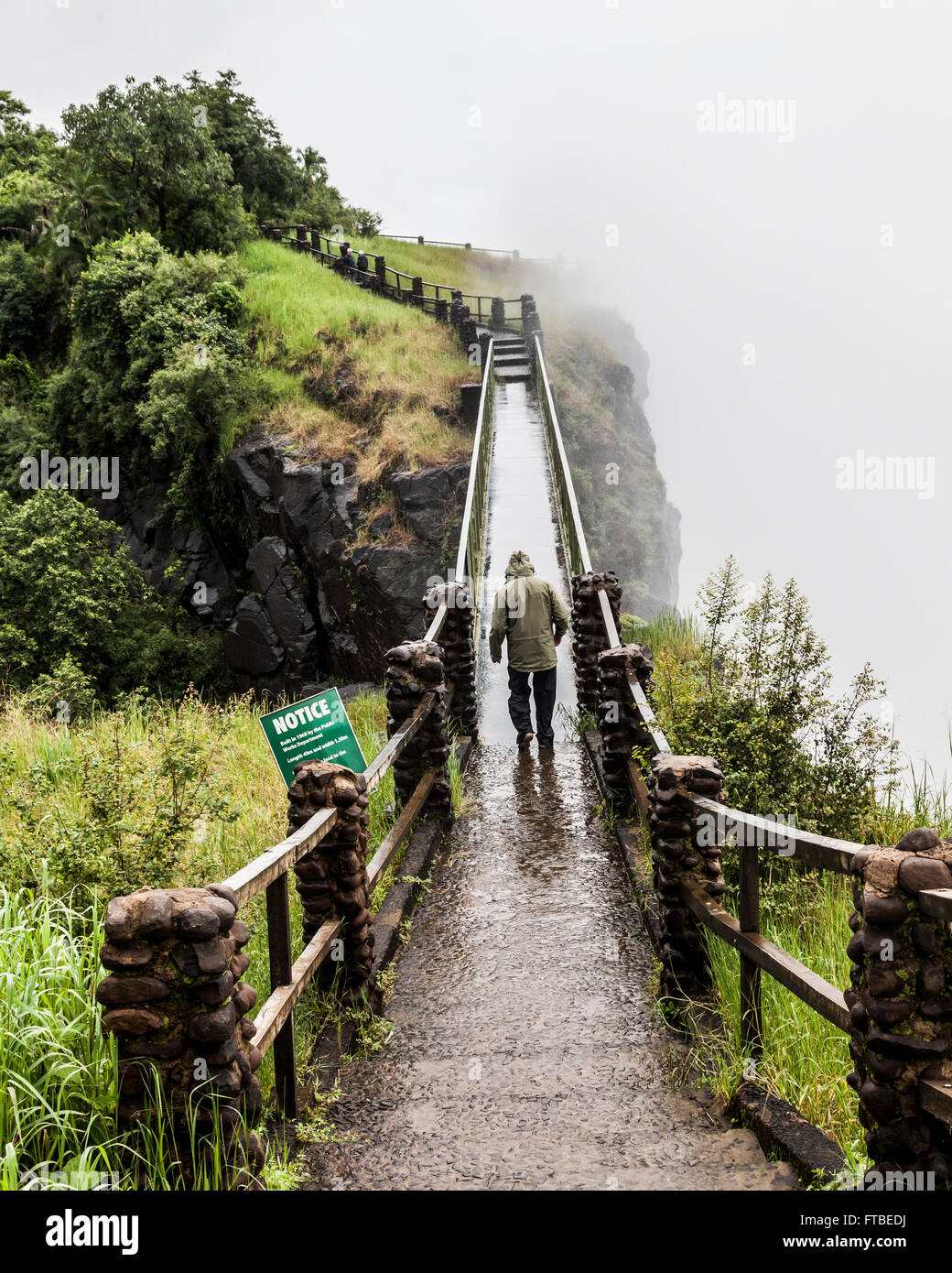 Tousist in rainwear at Knife Edge Bridge at Mosi-oa-Tunya (Victoria Falls) with heavy spray obscuring the view of the Falls. Stock Photo