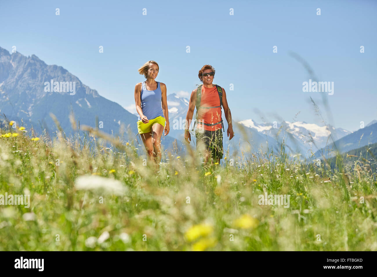 Man and woman walking in a meadow, mountains behind, from left Serles and Habicht and Stubai Glacier, Patsch, Rosengarten Stock Photo