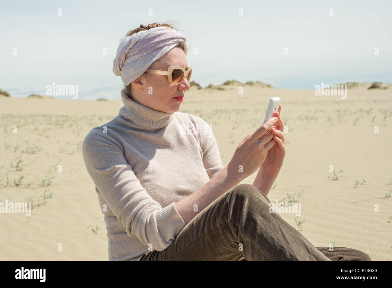Woman looking at a smartphone in the desert Stock Photo