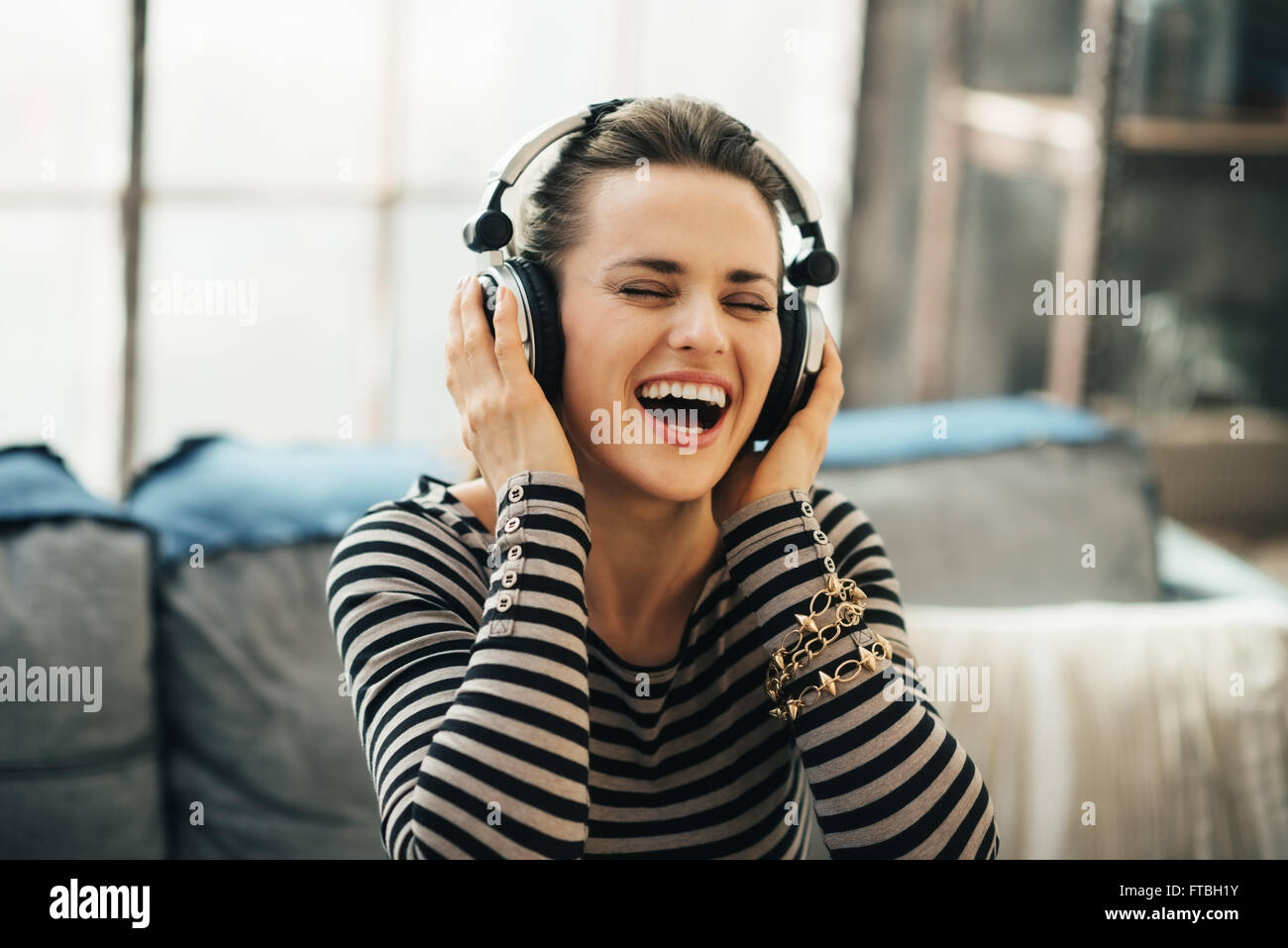 Shaking up time! Happy young woman listening to the music through ...
